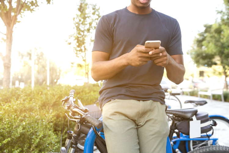 自転車にもたれかかりスマートフォンを操作する筋肉質な男性
